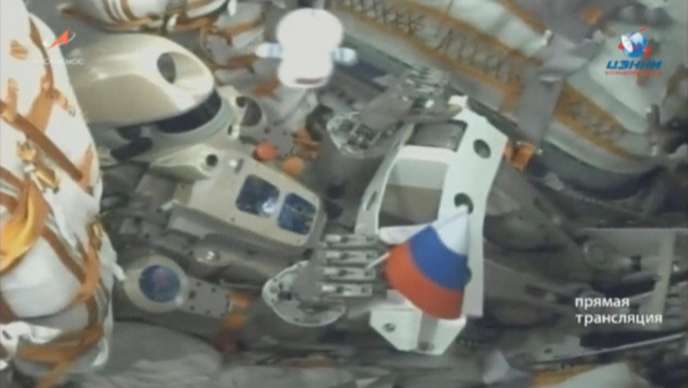 Bras robotique équipé d’un drapeau tricolore à l’intérieur d’un module spatial complexe