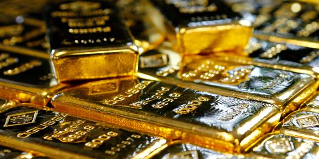 Plusieurs lingots d'or empilés les uns sur les autres avec des reflets lumineux sur leur surface brillante