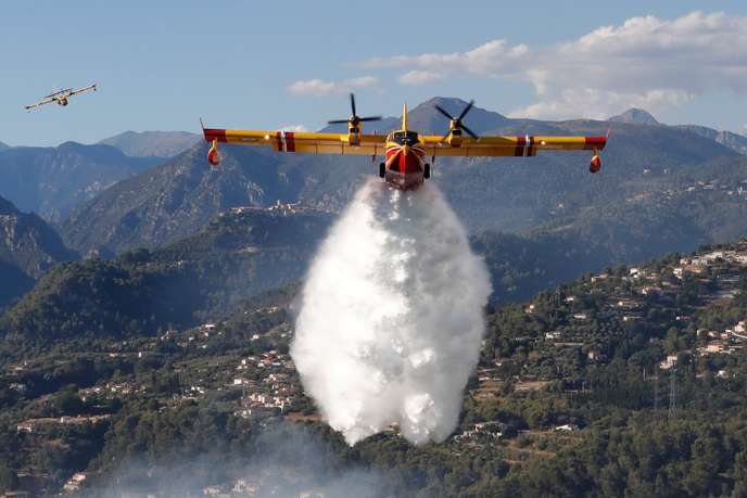 Avion de lutte contre les incendies larguant une grande quantité d eau au-dessus d une zone montagneuse et boisée