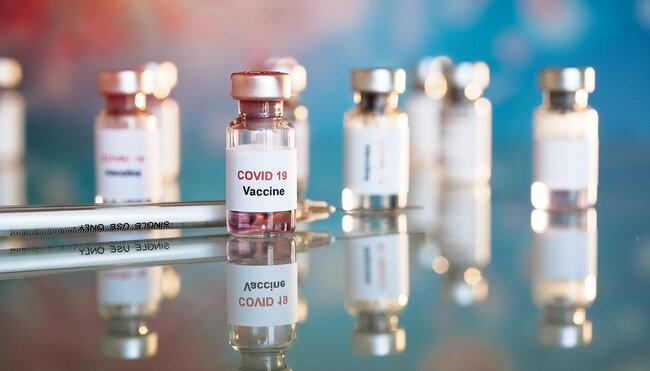 Flacons de vaccin marqués COVID-19 avec seringues alignées sur une surface réfléchissante floue
