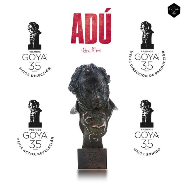 Quatre trophées Goya entourent un buste noir avec le titre rouge Adú sur fond blanc