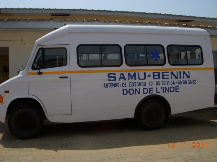 Véhicule blanc marqué SAMU-BENIN antenne de Cotonou don de l'Inde garé devant un bâtiment beige
