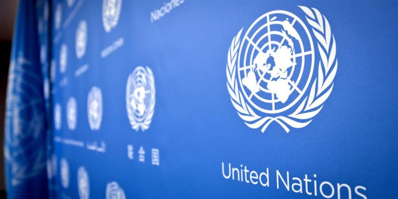 Un panneau bleu affichant le logo des Nations Unies et le texte United Nations en blanc sur un mur.