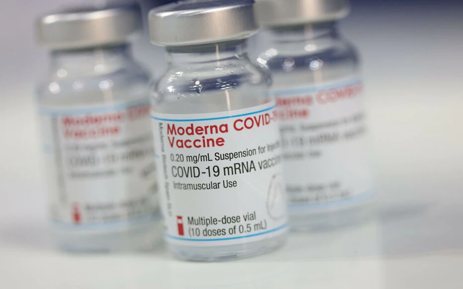 Plusieurs flacons de vaccin Moderna COVID-19 posés sur une surface blanche en gros plan