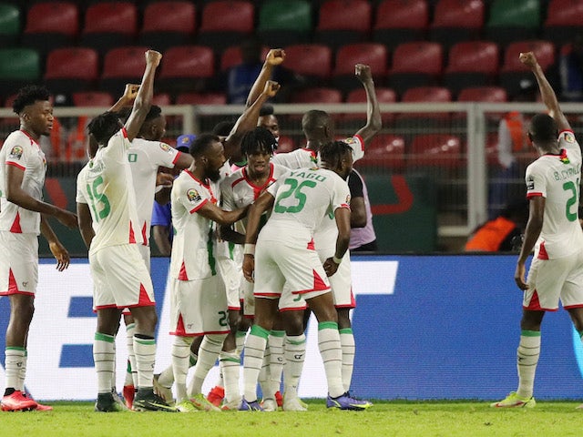 Des joueurs de football en maillots blancs et verts célèbrent un but ensemble sur le terrain avec les bras levés
