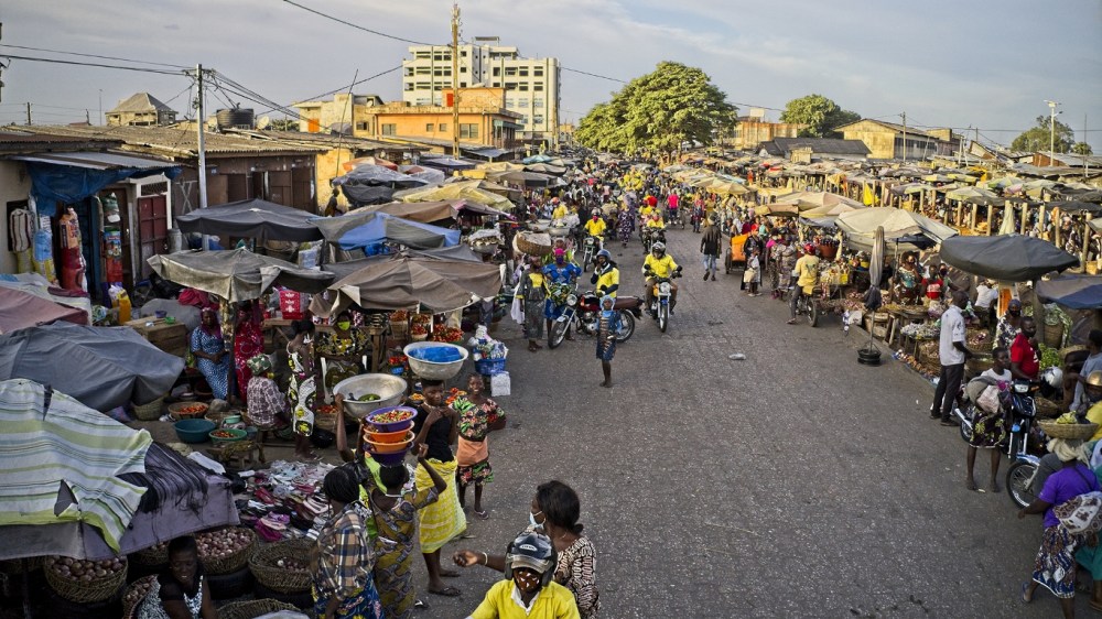 Marché très animé avec étals, marchands et clients sous ciel clair en fin d'après-midi