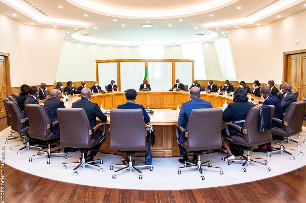 Personnes assises autour d’une grande table ronde dans une salle de réunion lumineuse avec parquet et murs clairs