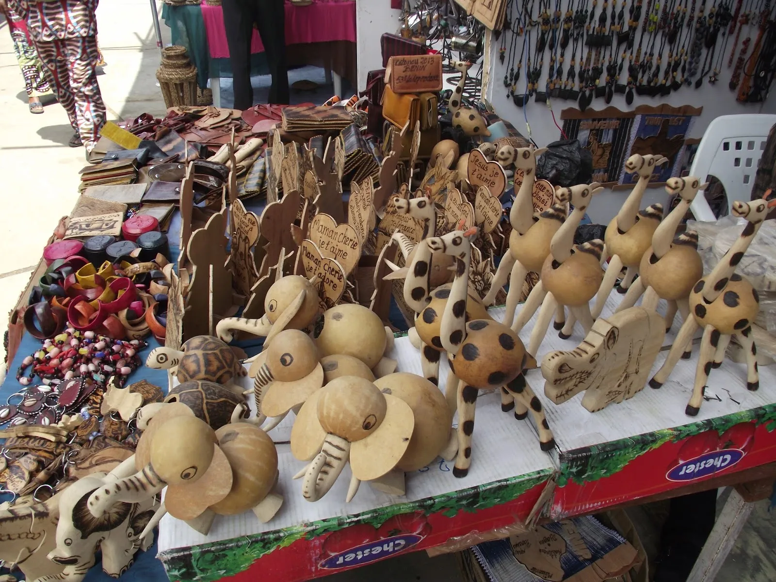Vêtements colorés et étalage d objets artisanaux en bois et cuir aux motifs animaux et messages divers