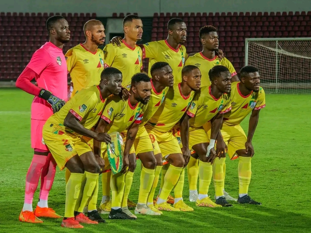 Onze joueurs de football en tenue jaune posant sur le terrain devant le but dans un stade vide