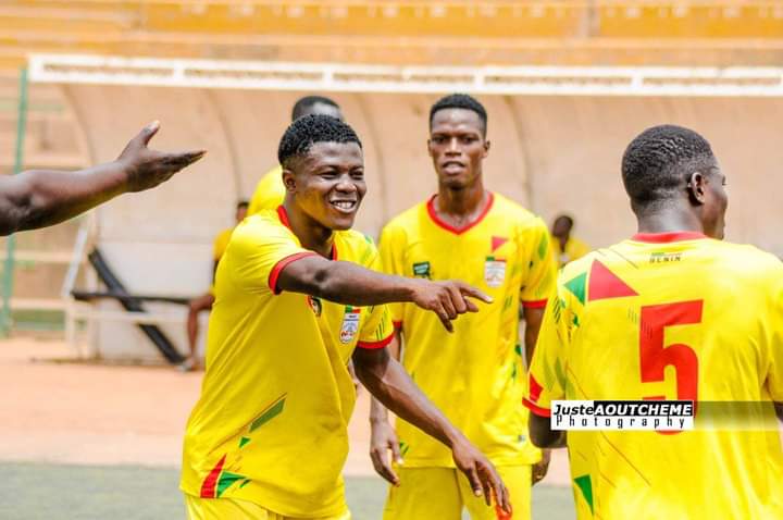Des joueurs en maillots jaunes sourient et gesticulent sur un terrain de football en pleine action