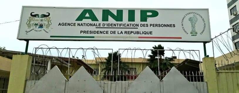 Entrée d’un bâtiment surmontée d’un panneau ANIP Agence Nationale d’Identification des Personnes avec fil barbelé sur le mur