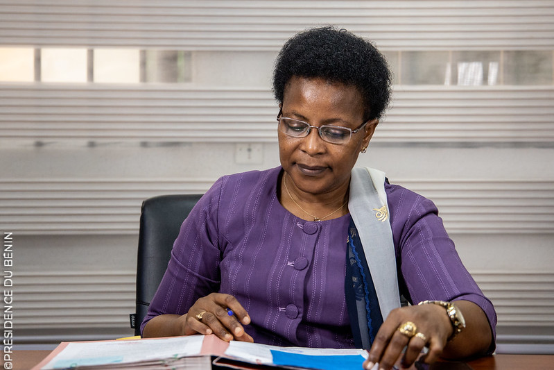 Femme assise à un bureau, lisant et feuilletant des documents dans un environnement de bureau lumineux