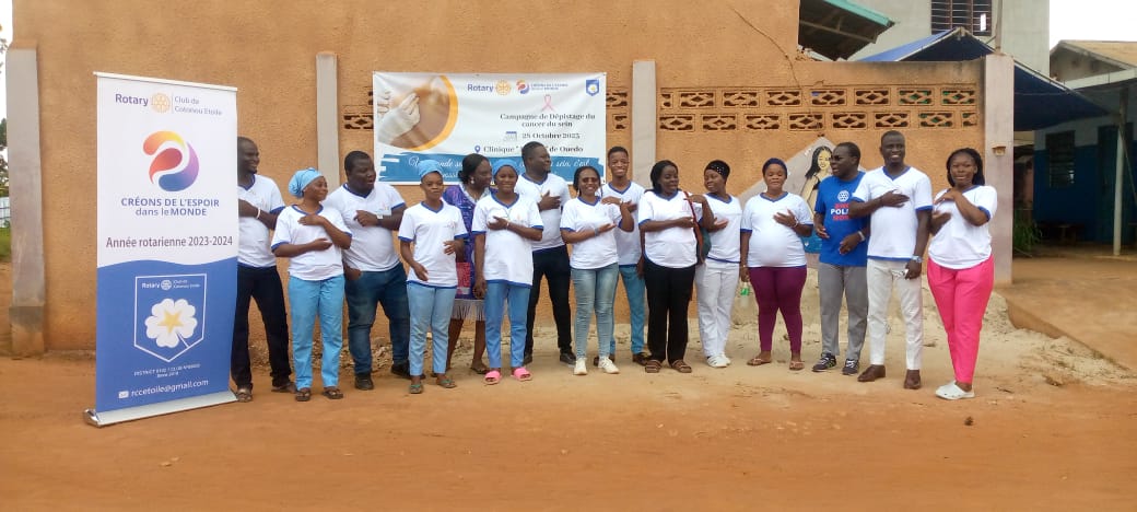 Un groupe de femmes en T-shirts blancs et pantalons divers posant devant un mur avec deux kakemonos de sensibilisation au dépistage du cancer.