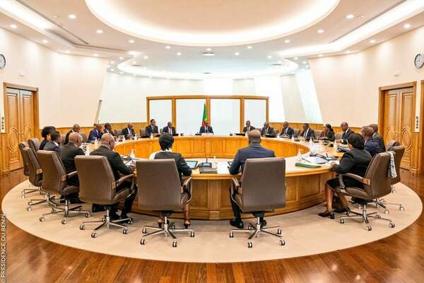 Personnes assises autour d'une grande table ronde dans une salle de réunion lumineuse au sol en bois