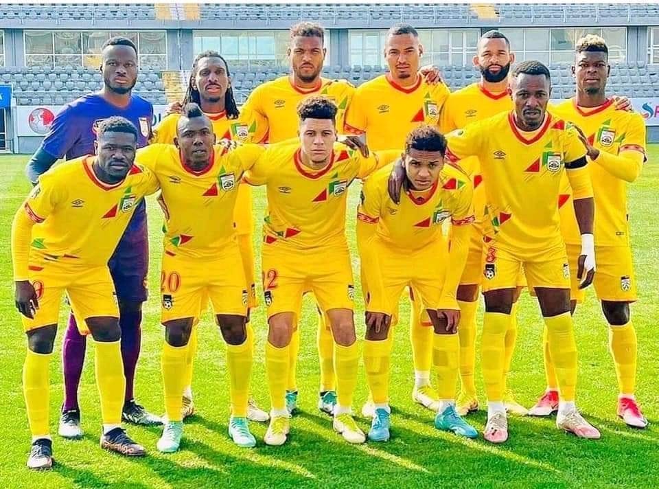 Onze joueurs de football en tenue jaune posant sur un terrain de football avant un match