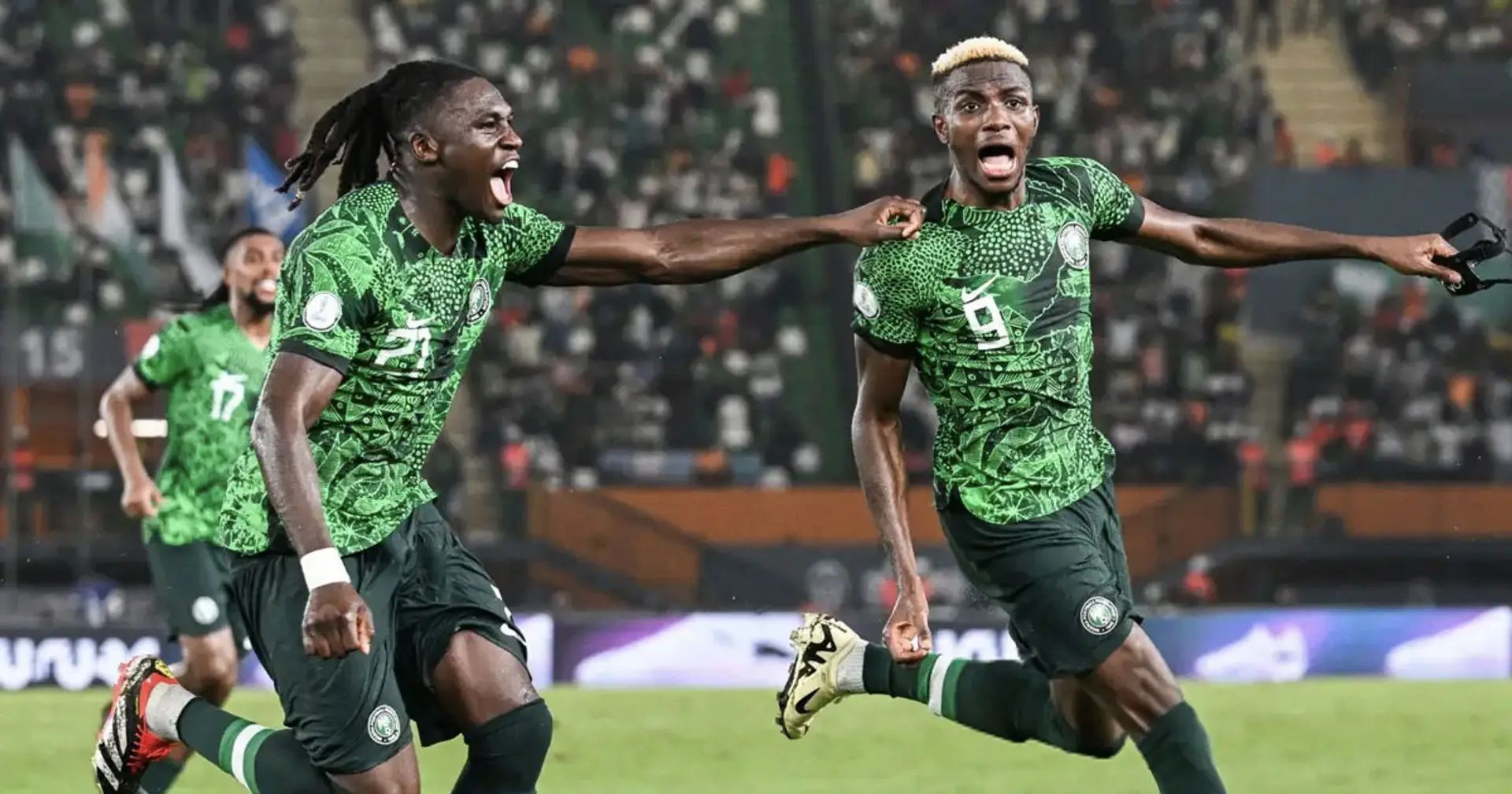 Deux joueurs en maillots verts célèbrent bruyamment un but lors d’un match de football dans un stade rempli de spectateurs