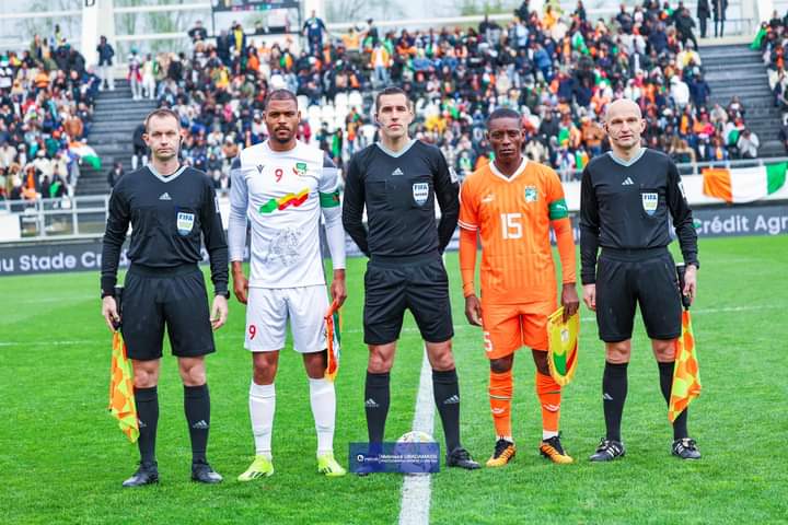 Deux capitaines d équipes de football posent avec trois arbitres au centre d un terrain devant des gradins remplis de spectateurs
