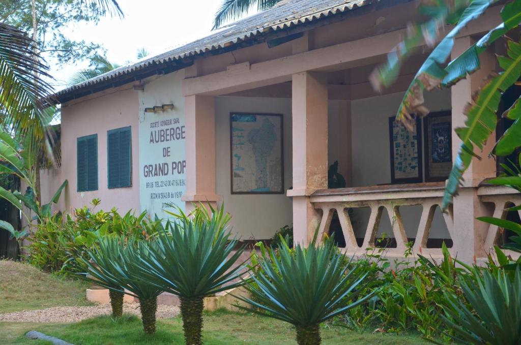 Façade d’un bâtiment avec panneau indiquant une auberge entourée de plantes vertes et arbres