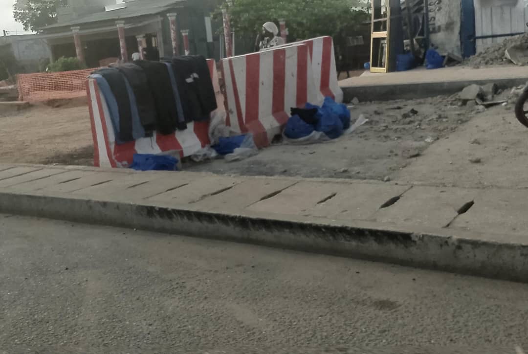 Larges blocs en plastique rouge et blanc barricadent une zone de chantier inachevé sur un trottoir en bordure de route