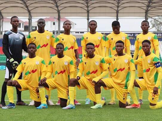 Onze joueurs de football en tenue jaune posant en formation sur un terrain sous une structure métallique