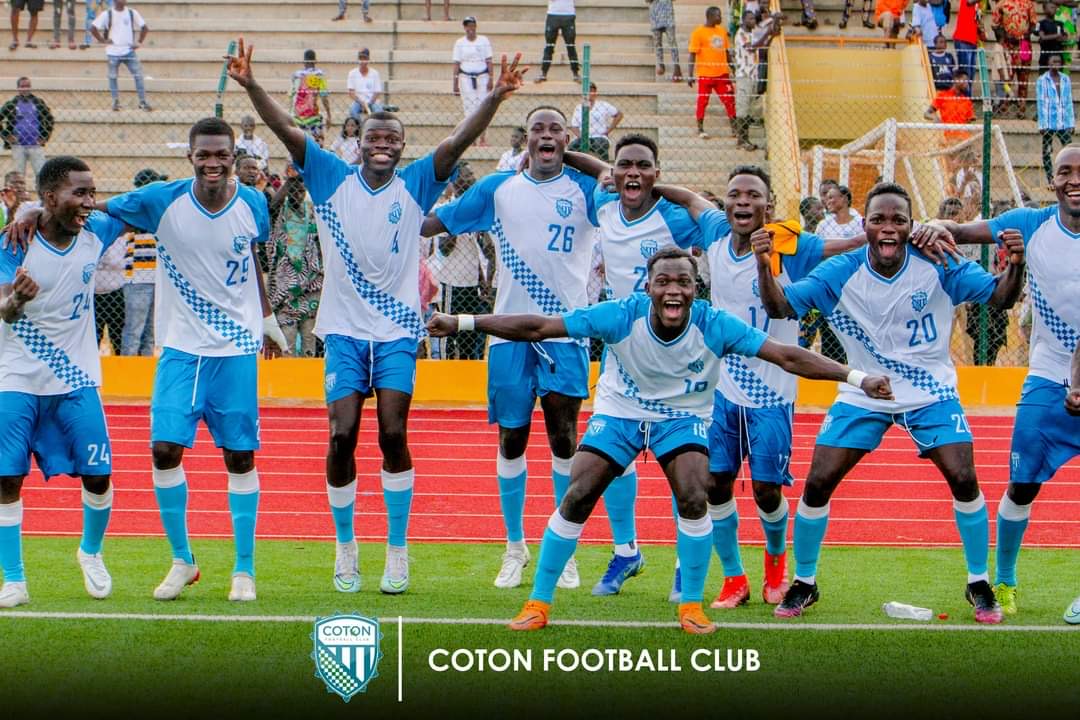 Joueurs en tenue bleue et blanche célébrant ensemble sur une pelouse de football devant des tribunes partiellement remplies