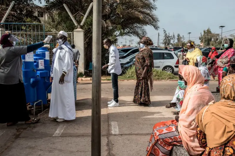 Personnes masquées faisant la queue à l'extérieur pour un test de température avant un contrôle sanitaire