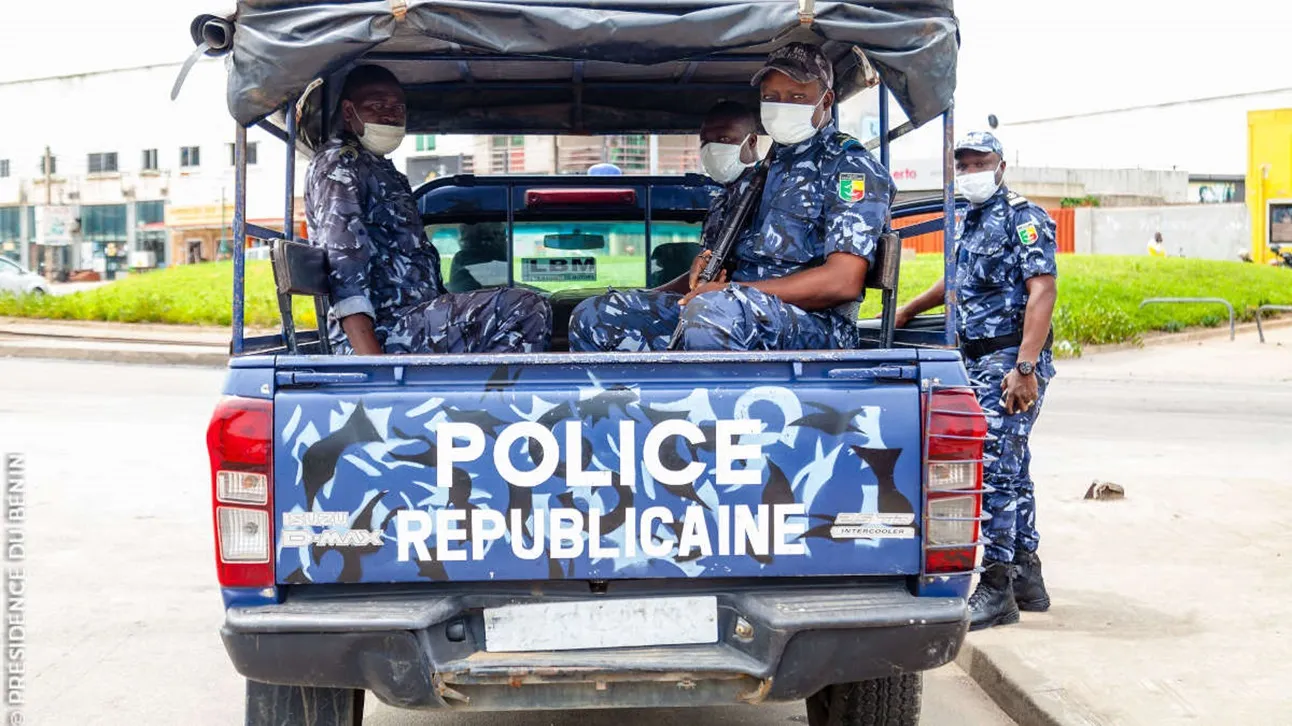 Quatre policiers masqués en tenue bleue camouflée dans une camionnette de police blanche et bleue