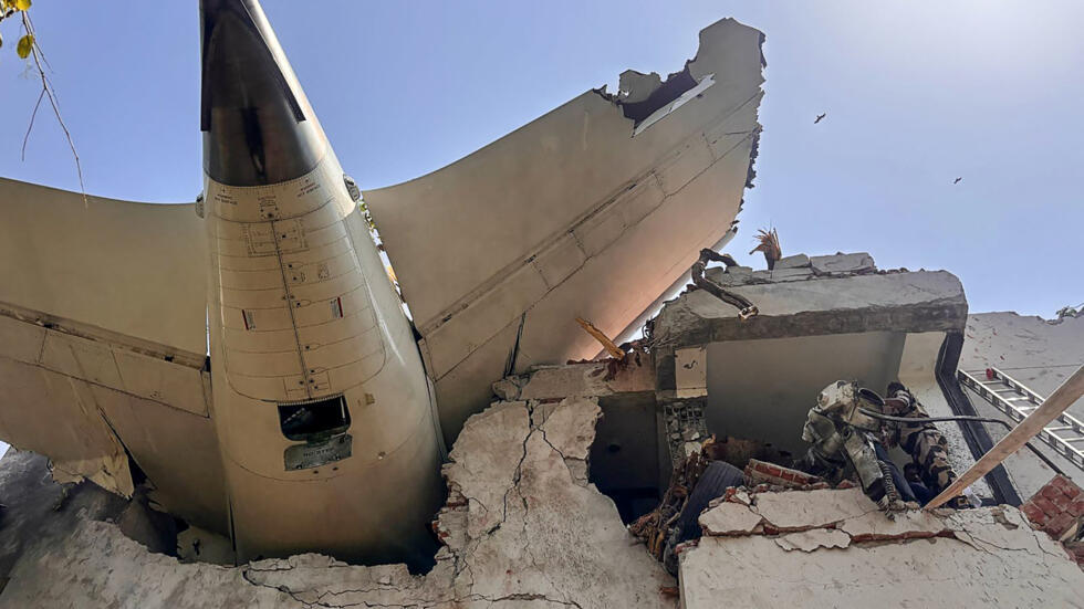 Partie arrière d’un avion encastrée dans un immeuble effondré avec des personnes sur les décombres