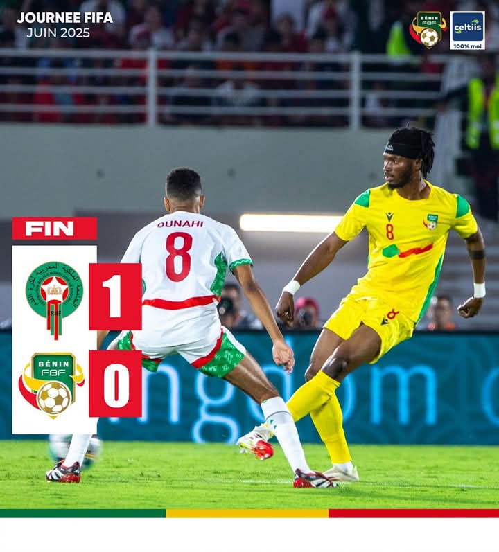 Deux joueurs en action sur un terrain de football, l’un en tenue blanche rouge vert et l’autre en tenue jaune vert rouge