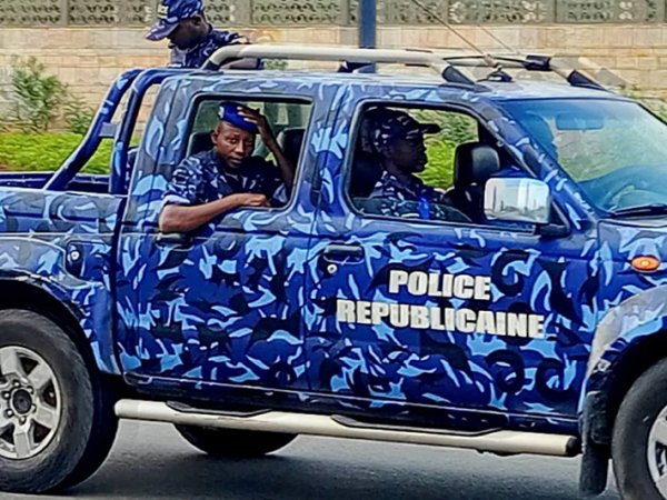 Quatre policiers en uniforme bleu dans un véhicule tout-terrain bleu camouflé marqué Police Républicaine