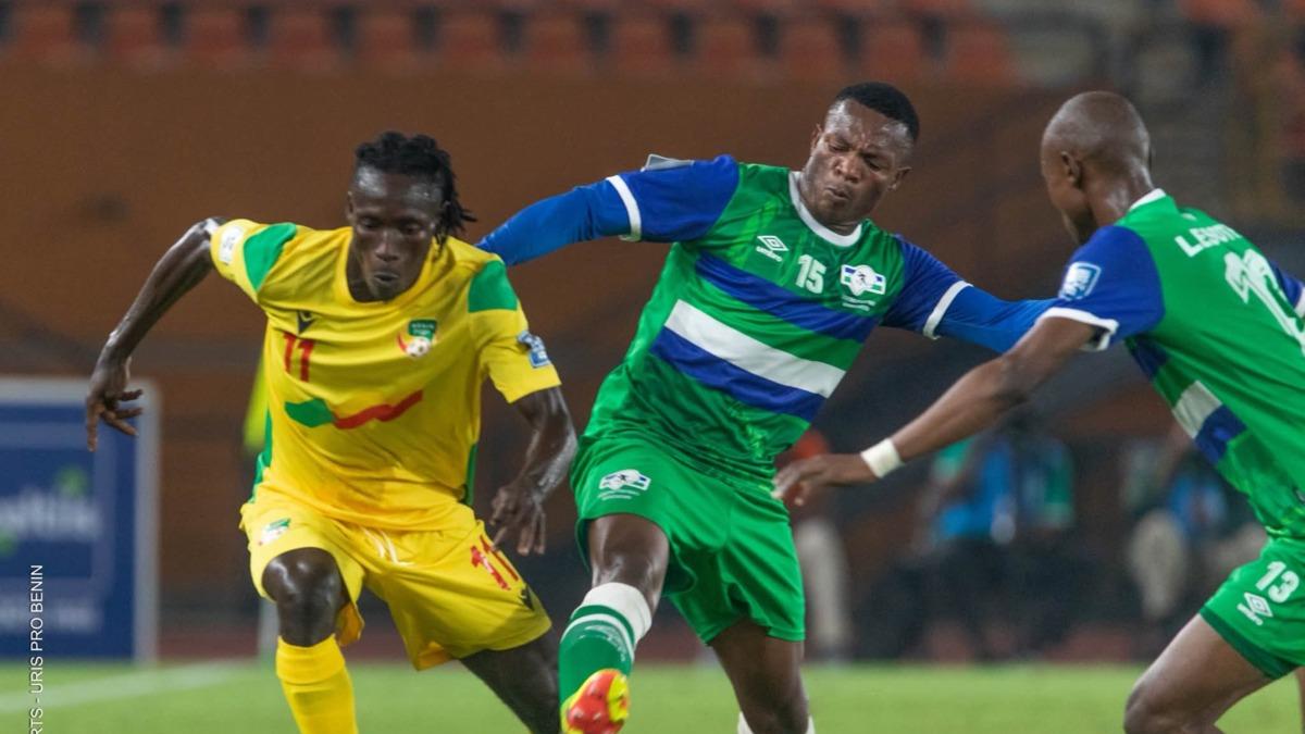 Trois joueurs en duel au ballon lors d un match de football avec un joueur en maillot jaune et deux en maillot vert bleu et blanc