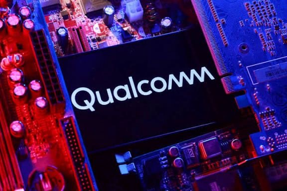 Circuit électronique avec une puce noire portant le logo Qualcomm éclairée en bleu et rouge