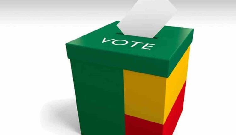 Urne tricolore verte jaune rouge avec une feuille insérée au-dessus et le mot VOTE inscrit dessus