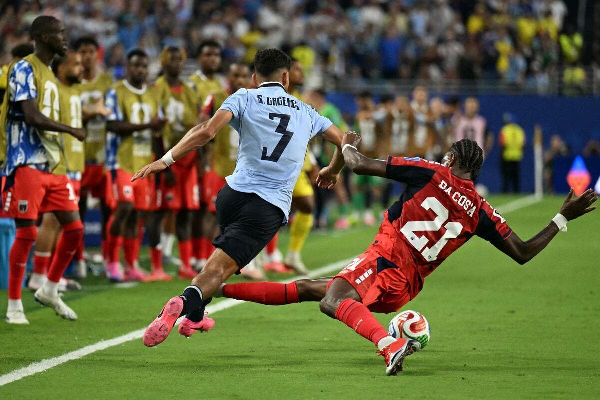 Deux joueurs en action lors d'un match de football, l’un tente de récupérer le ballon pendant que l’autre glisse au sol près de la ligne blanche du terrain