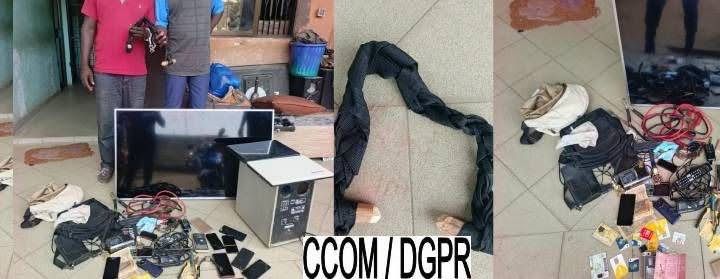 Objets divers dont un téléviseur, un ordinateur, plusieurs téléphones portables et câbles étalés sur le sol devant deux hommes debout partiellement visibles