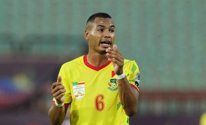 Un joueur de football en maillot jaune numéro 6 gesticule sur le terrain pendant un match