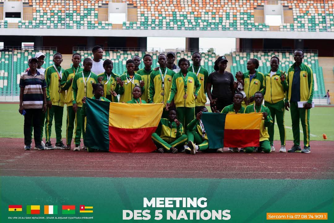 Groupe de jeunes sportifs en tenue verte et jaune posant dans un stade avec deux drapeaux tricolores rouge, jaune, vert