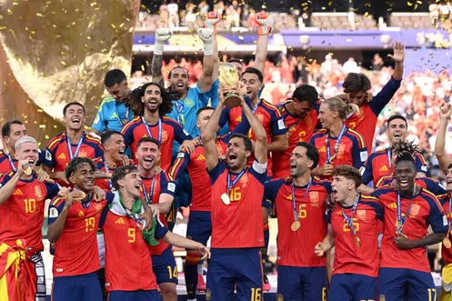 Joueurs en maillot rouge célébrant la victoire avec une coupe et des confettis dorés en arrière-plan