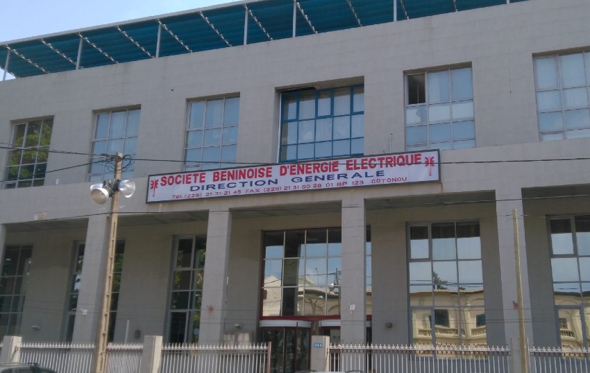 Façade d'un bâtiment administratif avec une enseigne indiquant une société d'énergie électrique et une clôture métallique devant
